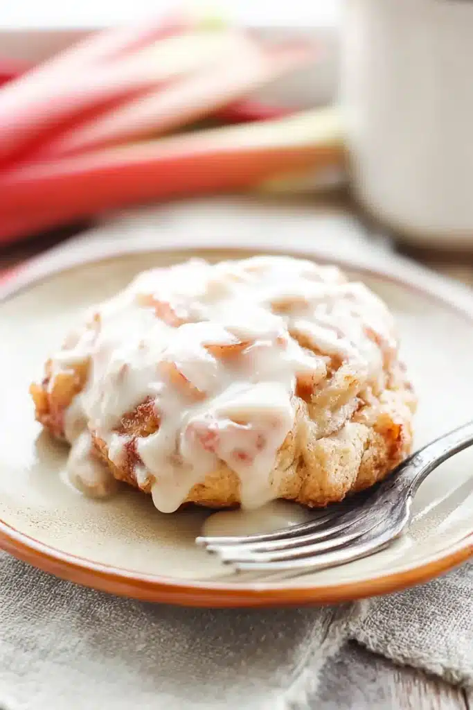 Baked Rhubarb Fritters Recipe You’ll Love 1 Baked rhubarb fritter with creamy glaze on white plate