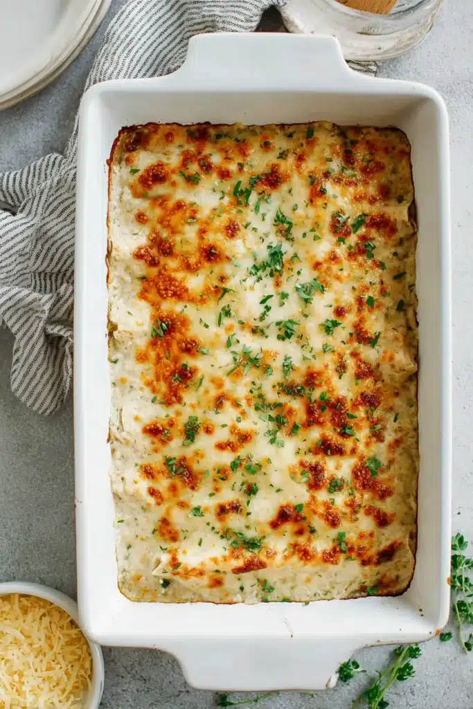 Baked Sour Cream Chicken Enchiladas with golden melted cheese in dish