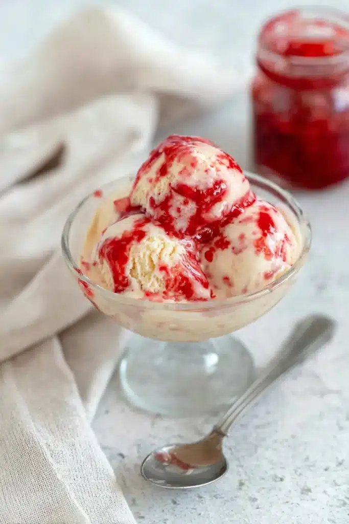 Rhubarb Ice Cream: A Creamy, Tangy Homemade Treat 4 Rhubarb ice cream with red fruit sauce served in glass dessert bowl