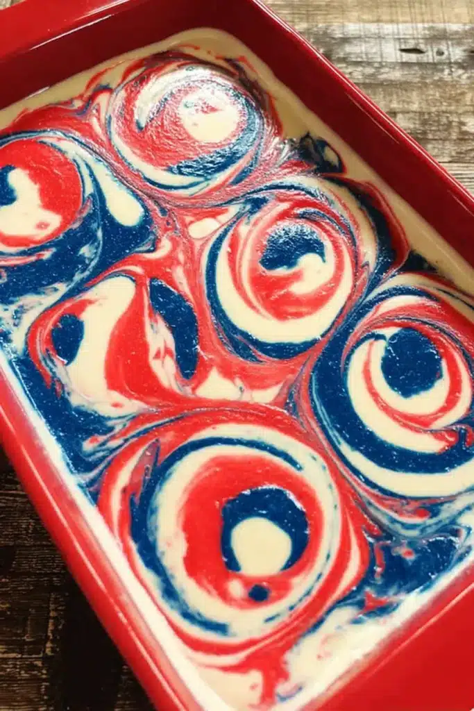 Patriotic Poke Cake That’s Bright, Easy, and Crowd-Pleasing 2 Patriotic Poke Cake batter with red white and blue swirls in baking dish