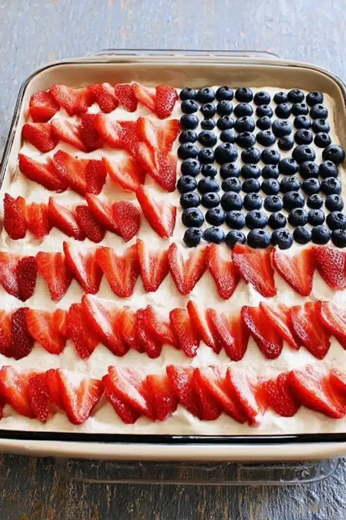 American Flag Strawberry Poke Cake 2 American Flag Strawberry Poke Cake decorated with strawberries and blueberries