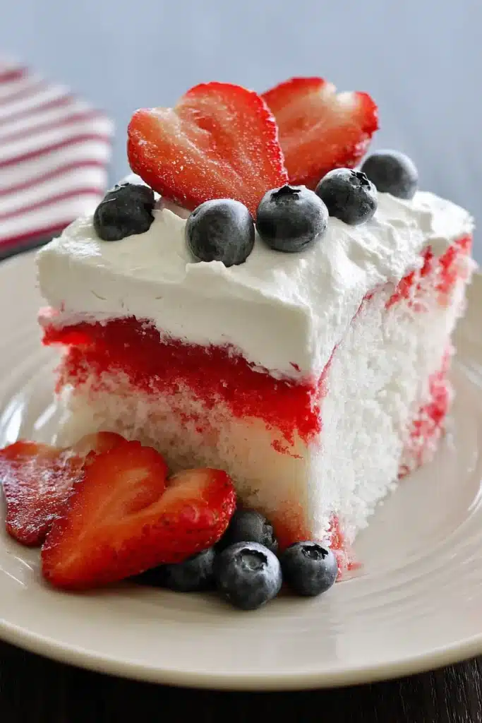 American Flag Strawberry Poke Cake 1 American Flag Strawberry Poke Cake slice topped with strawberries and blueberries