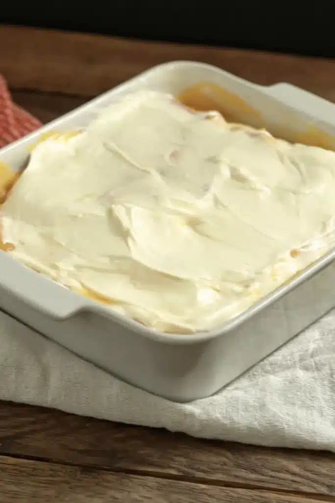 Unbaked Peaches and Cream Pie with creamy topping in glass dish