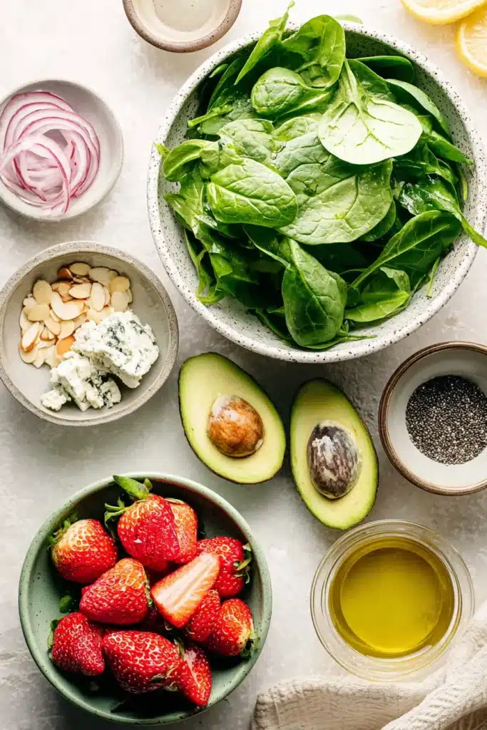 Strawberry Avocado Spinach Salad ingredients with spinach, strawberries, avocado, almonds, and cheese