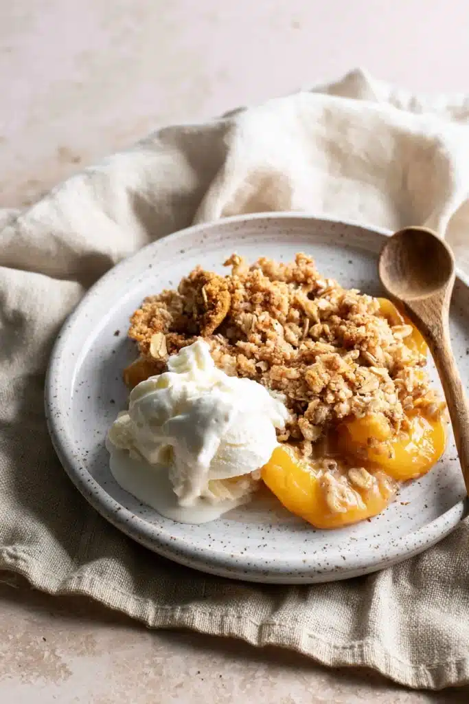 Peach Crisp with Canned Peaches 1 Peach Crisp with Canned Peaches served with vanilla ice cream on a plate