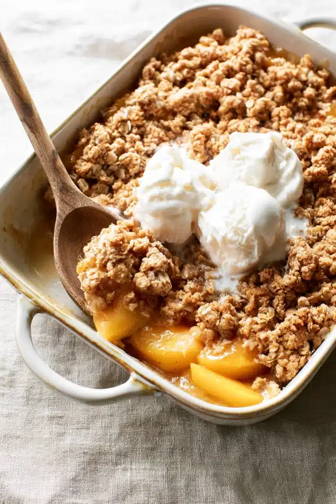 Peach Crisp with Canned Peaches 2 Peach crisp with canned peaches topped with melting vanilla ice cream in a baking dish